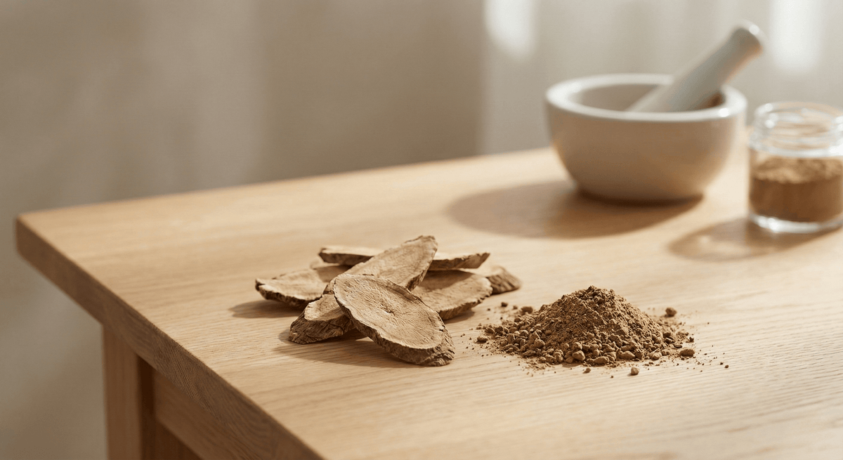 Sliced tongkat ali root and ground powder on a wooden table beside a mortar and pestle — testosterone and energy support for men